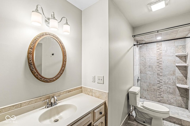 bathroom featuring tiled shower, vanity, and toilet