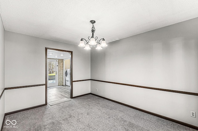 carpeted spare room with a notable chandelier, washer / dryer, and a textured ceiling