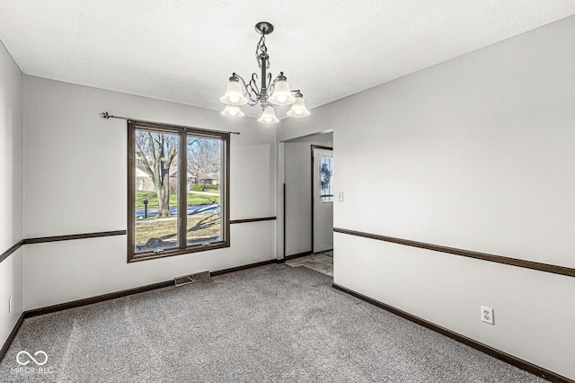 unfurnished room with carpet flooring, a textured ceiling, and a notable chandelier