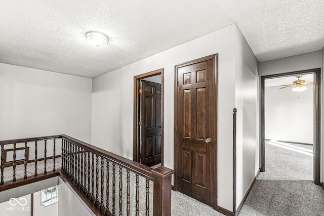 corridor featuring a textured ceiling and light colored carpet