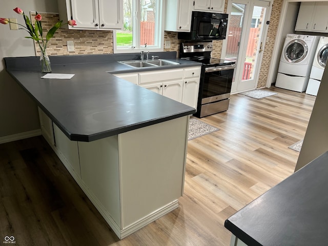 kitchen featuring light wood-type flooring, dark countertops, stainless steel range with electric stovetop, washer and clothes dryer, and a sink