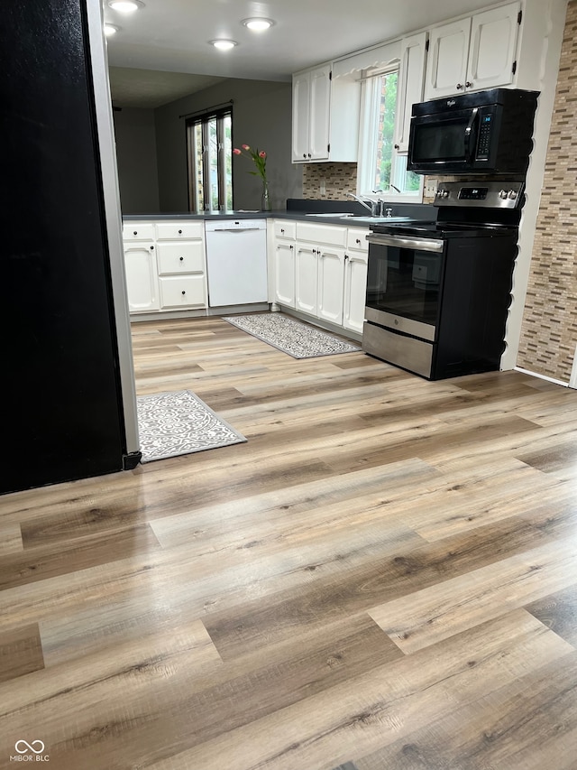 kitchen with dark countertops, white cabinets, appliances with stainless steel finishes, and light wood-style floors