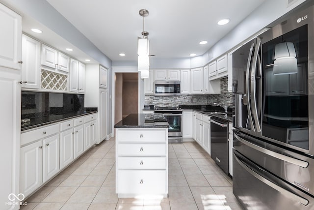 kitchen featuring white cabinetry, stainless steel appliances, backsplash, decorative light fixtures, and a kitchen island