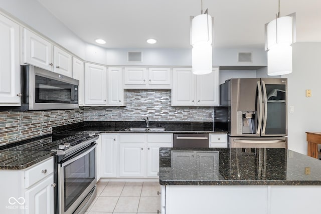 kitchen featuring dark stone counters, white cabinets, hanging light fixtures, and appliances with stainless steel finishes