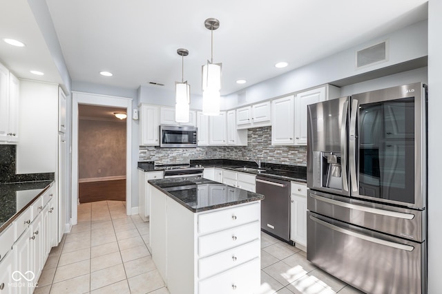 kitchen featuring a center island, dark stone counters, pendant lighting, white cabinets, and appliances with stainless steel finishes