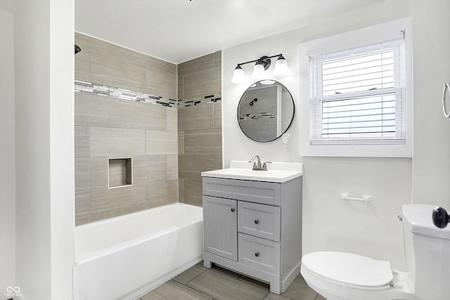 full bathroom featuring vanity, tiled shower / bath combo, and toilet