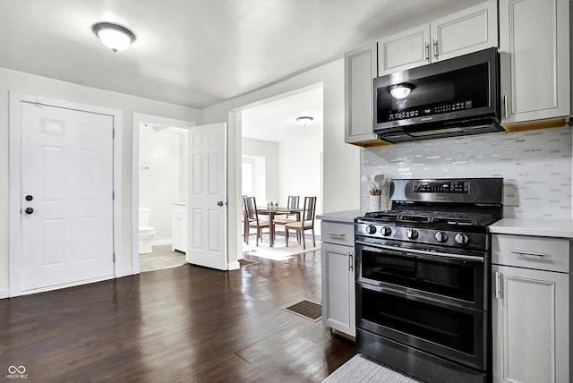 kitchen featuring appliances with stainless steel finishes, gray cabinets, tasteful backsplash, and dark wood-type flooring