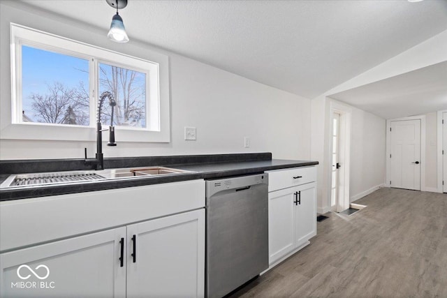 kitchen featuring white cabinetry, sink, light hardwood / wood-style flooring, stainless steel dishwasher, and lofted ceiling