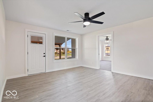 empty room featuring light wood-type flooring, plenty of natural light, and ceiling fan