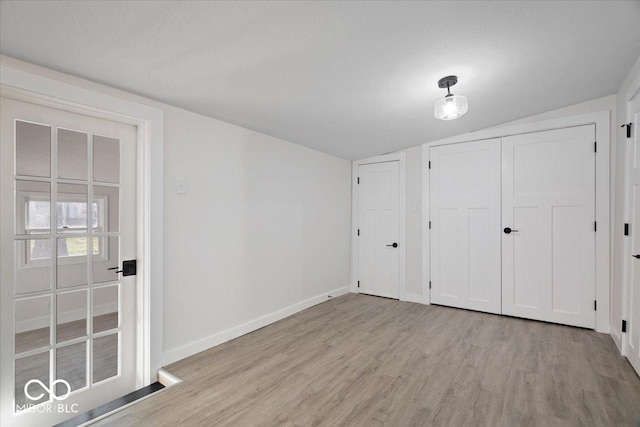 unfurnished bedroom with light hardwood / wood-style floors, a closet, and lofted ceiling