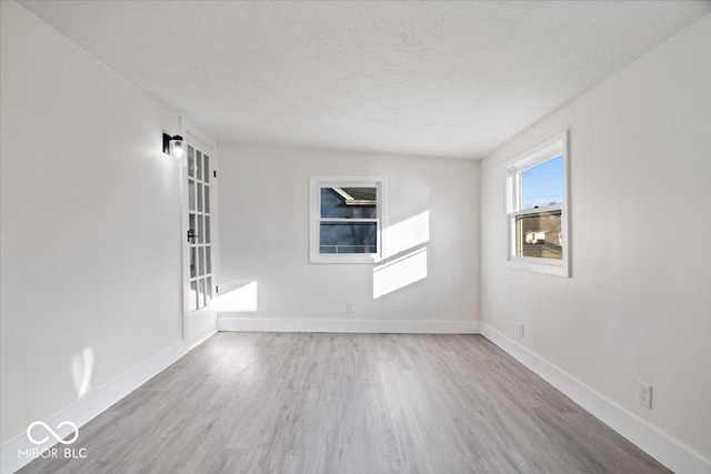 unfurnished room featuring light hardwood / wood-style floors and a textured ceiling