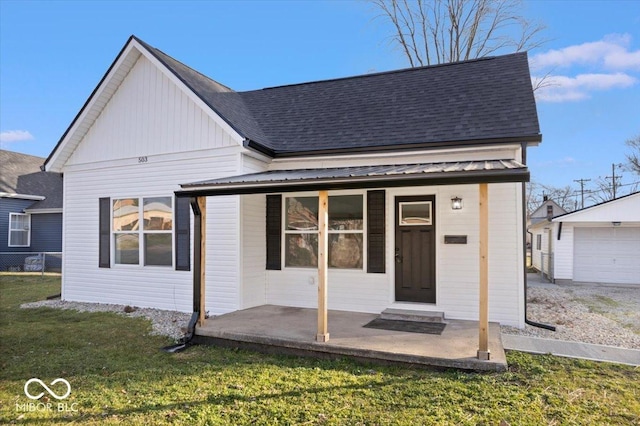 rear view of house featuring a yard, a garage, and an outdoor structure