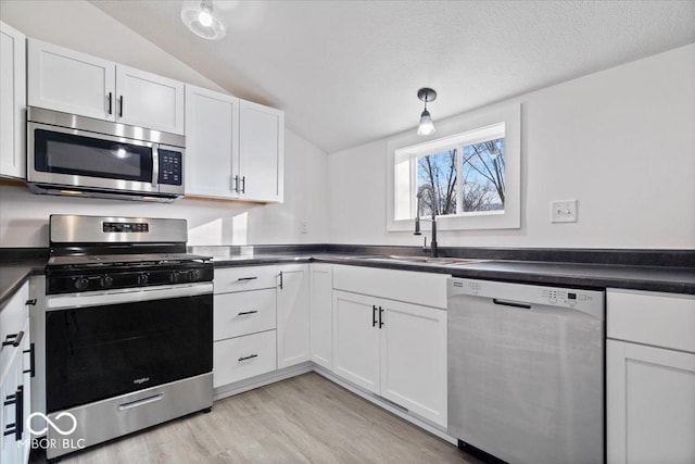 kitchen featuring white cabinets, sink, hanging light fixtures, vaulted ceiling, and stainless steel appliances