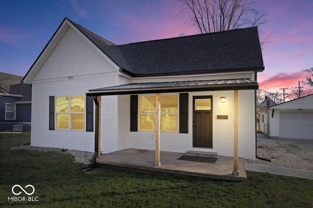 back house at dusk with a yard, an outdoor structure, and a garage