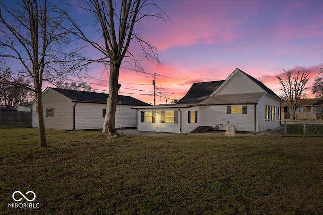 back house at dusk with a patio, cooling unit, and a lawn