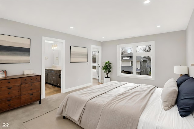 bedroom with ensuite bathroom and light carpet