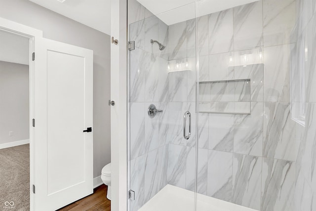 bathroom with hardwood / wood-style flooring, toilet, and a shower with shower door