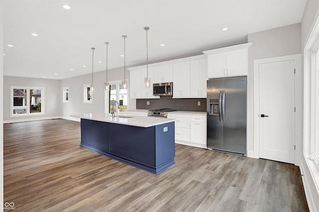 kitchen featuring pendant lighting, stainless steel appliances, white cabinetry, and sink