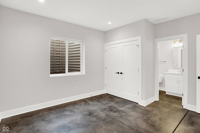 unfurnished bedroom featuring ensuite bath, sink, and a closet