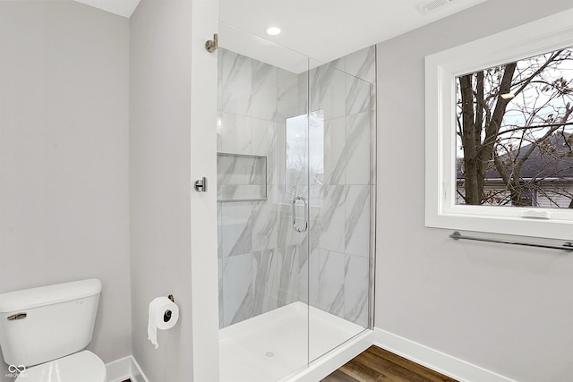 bathroom featuring hardwood / wood-style flooring, a shower with door, and toilet