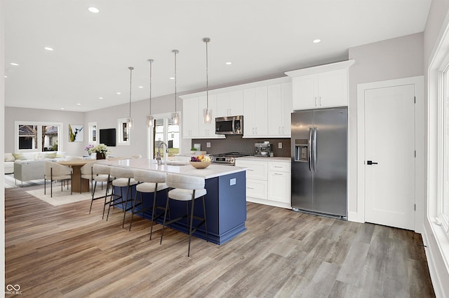 kitchen featuring white cabinetry, sink, a center island with sink, and appliances with stainless steel finishes