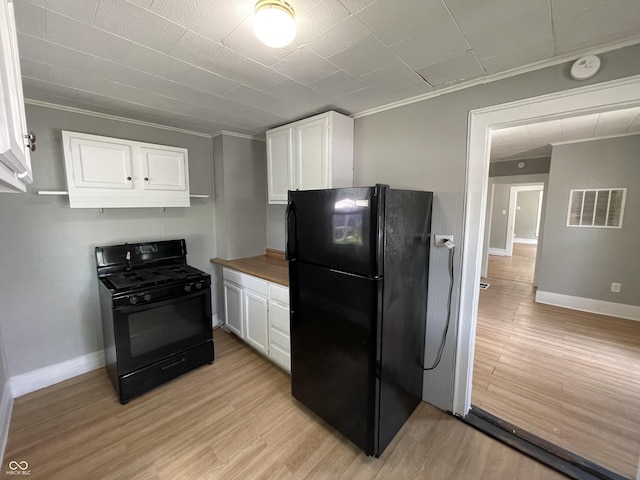 kitchen featuring wooden counters, white cabinets, and black appliances