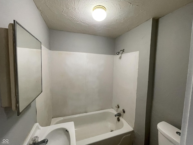 full bathroom with a textured ceiling,  shower combination, toilet, and sink