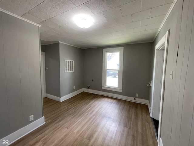 interior space with crown molding, wood walls, and hardwood / wood-style flooring