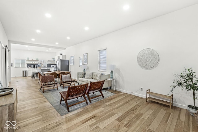 living room with a barn door and light hardwood / wood-style flooring