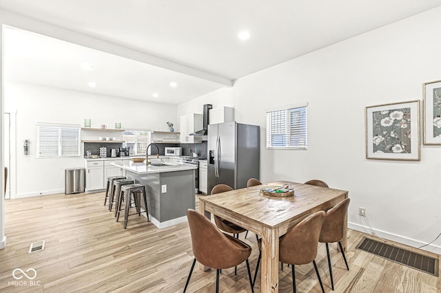 dining room with a healthy amount of sunlight, sink, and light hardwood / wood-style flooring