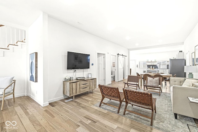 living room featuring a barn door and light hardwood / wood-style flooring