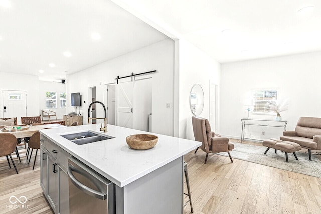 kitchen featuring dishwasher, sink, a barn door, gray cabinets, and a center island with sink