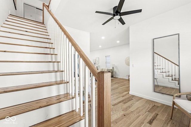 stairway with ceiling fan and wood-type flooring