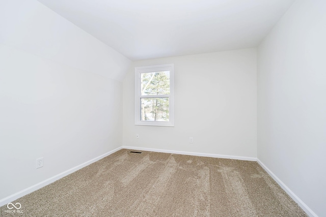 empty room featuring vaulted ceiling and carpet flooring