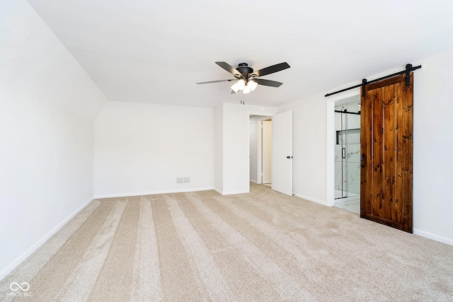 carpeted spare room featuring ceiling fan and a barn door