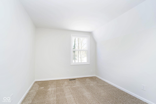 additional living space featuring lofted ceiling and light carpet