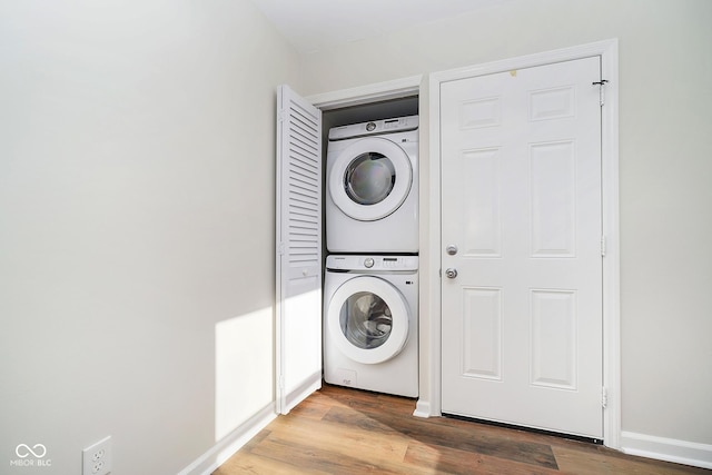 laundry area featuring stacked washer / drying machine and hardwood / wood-style flooring