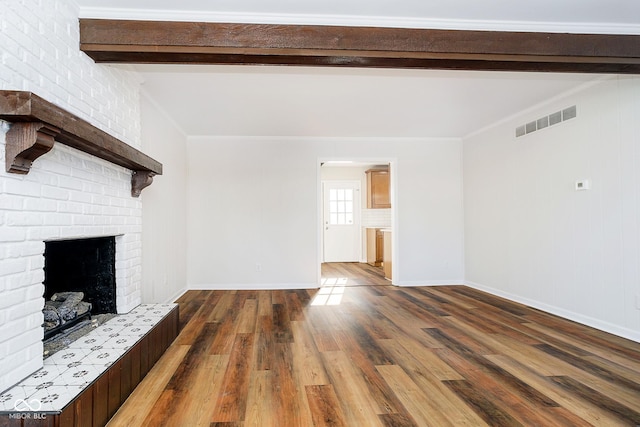 unfurnished living room with crown molding, a brick fireplace, hardwood / wood-style flooring, and beam ceiling