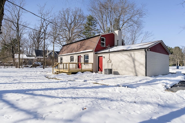 snow covered rear of property with central AC and a deck