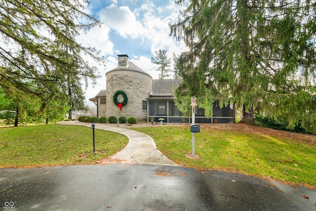 view of front of house with a front yard and a sunroom