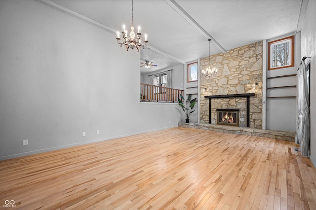 unfurnished living room featuring ceiling fan with notable chandelier, light wood-type flooring, a stone fireplace, and crown molding