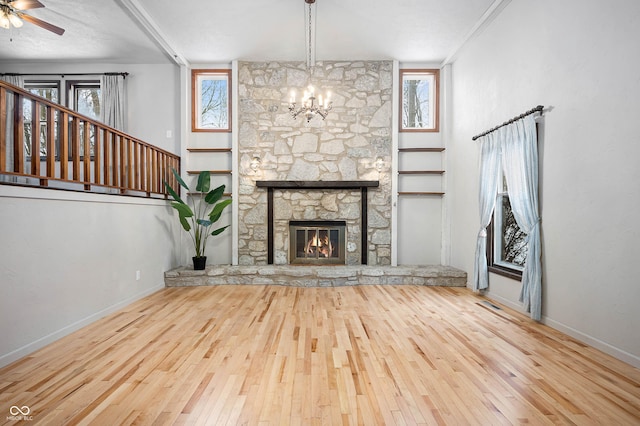 unfurnished living room featuring a stone fireplace, plenty of natural light, ornamental molding, and hardwood / wood-style flooring