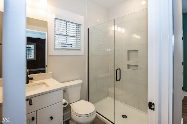 bathroom featuring toilet, a shower with shower door, and vanity