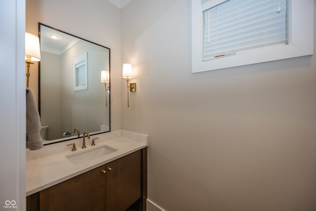 bathroom with toilet, vanity, and ornamental molding