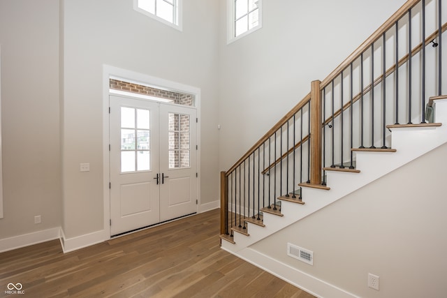 entrance foyer featuring a towering ceiling, french doors, and hardwood / wood-style flooring