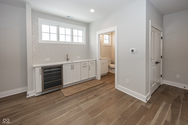 bar with wine cooler, dark hardwood / wood-style floors, decorative backsplash, sink, and white cabinetry