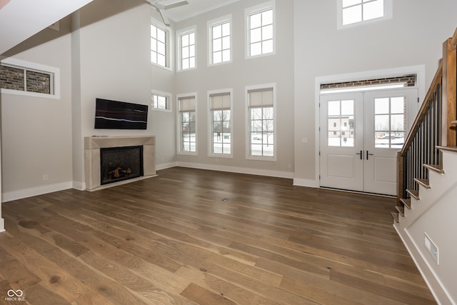 unfurnished living room with a high ceiling, dark hardwood / wood-style flooring, and french doors