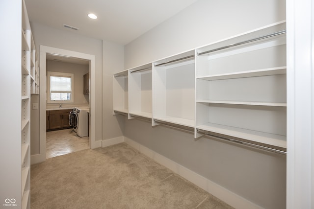 walk in closet featuring sink and light colored carpet