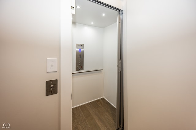 interior details featuring elevator and wood-type flooring