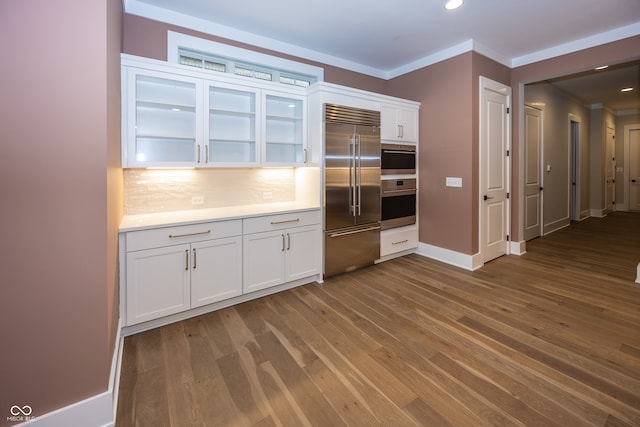 kitchen with backsplash, light hardwood / wood-style floors, built in refrigerator, and white cabinetry